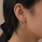 Close-up of an ear wearing a gold earring with small stones.