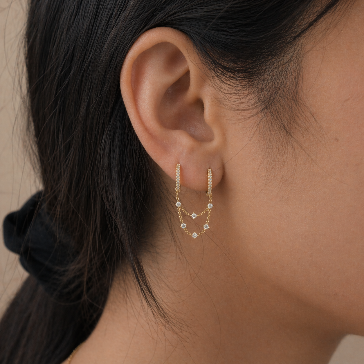 Close-up of an ear wearing a gold earring with small stones.