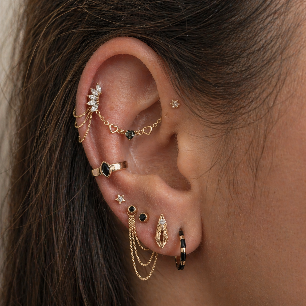 Close-up of an ear with multiple gold earrings and rings.