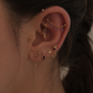 Close-up of an ear with multiple gold earrings against a blurred background