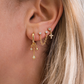 Close-up of an ear wearing gold earrings with small charms.