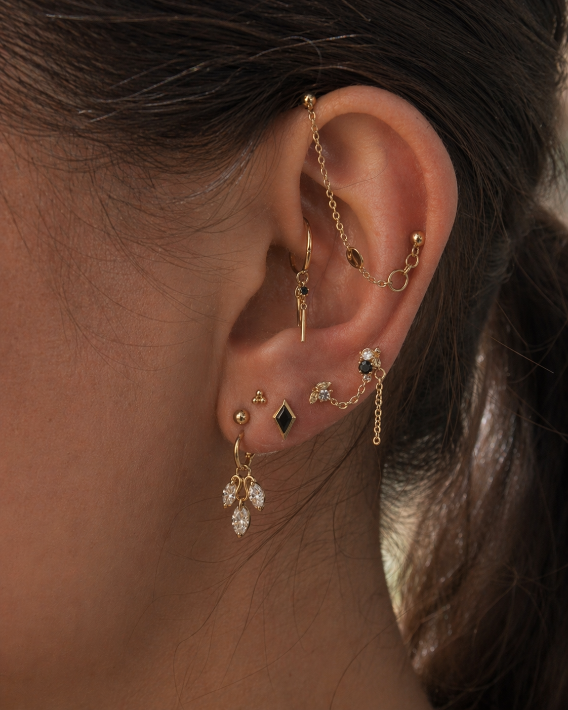 Close-up of an ear with multiple gold earrings and a blurred background