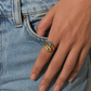 Hand wearing a gold ring with a turquoise stone against a denim background