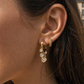 Close-up of an ear wearing gold hoop earrings with small round stones.