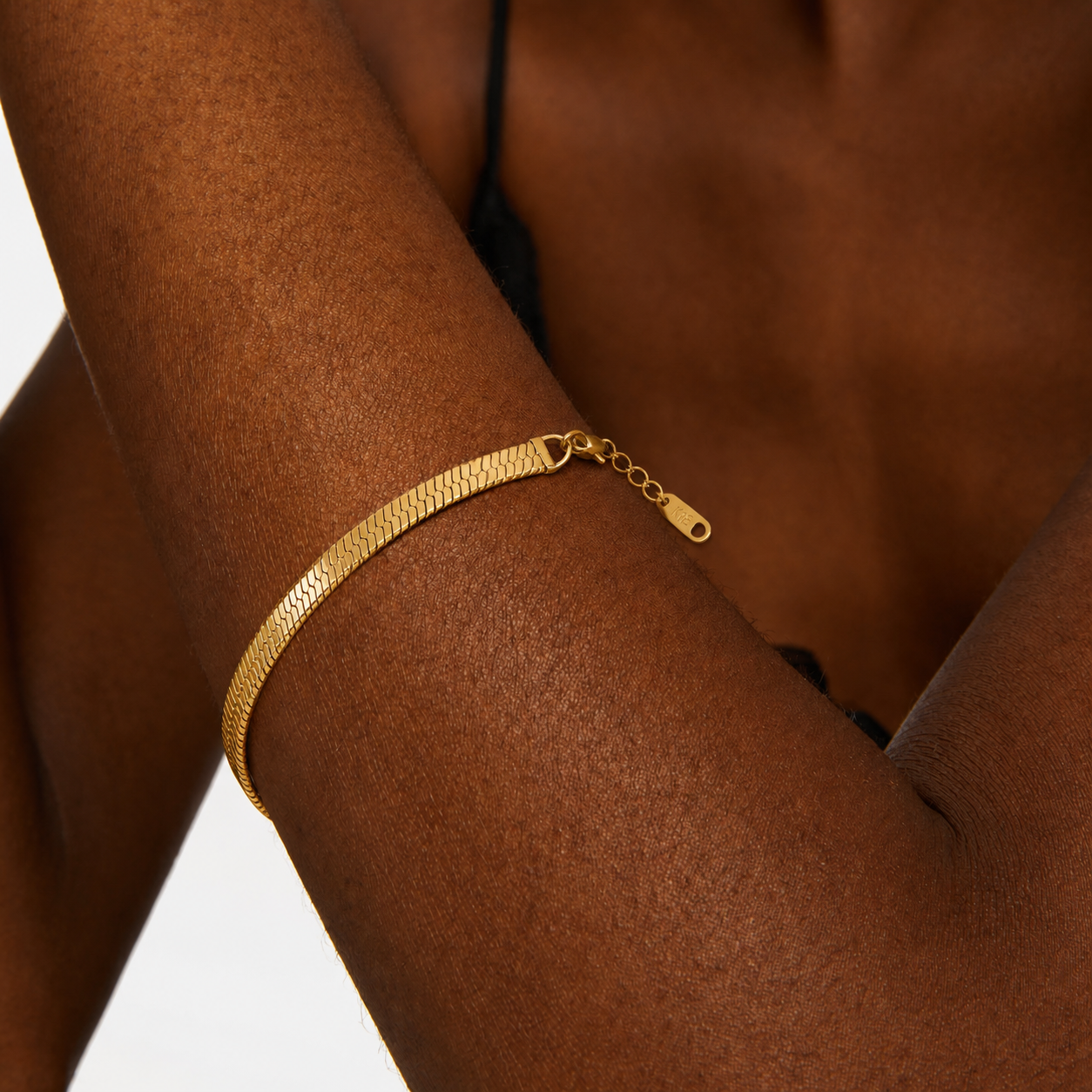 Gold bracelet on a person's wrist with a neutral background