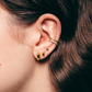 Close-up of an ear with gold earrings and a ring, with brown hair.