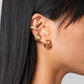 Close-up of an ear wearing gold hoop earrings with a neutral background
