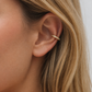 Close-up of an ear wearing a gold hoop earring with blonde hair.
