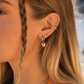 Close-up of a person wearing gold earrings and necklaces with a blurred background
