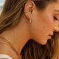 Close-up of a woman wearing gold hoop earrings with a blurred background