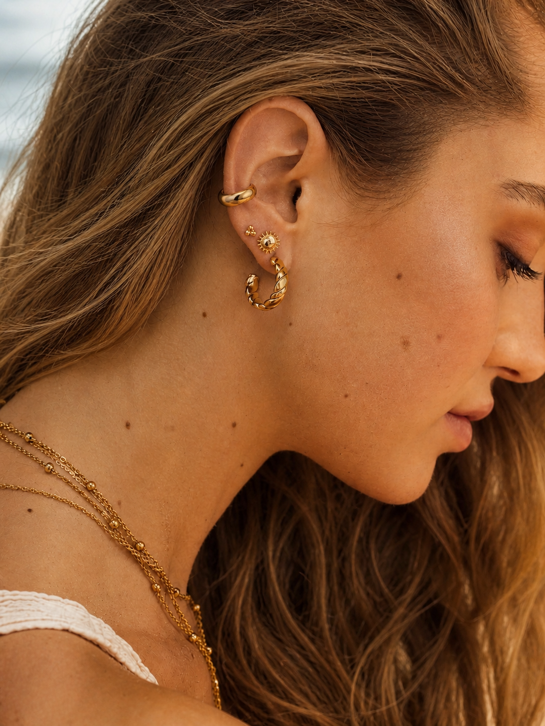 Close-up of a woman wearing gold hoop earrings with a blurred background