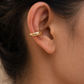 Close-up of an ear wearing a gold hoop earring with blurred hair and skin in the background