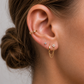 Close-up of an ear with gold hoop earrings and a small stud earring.