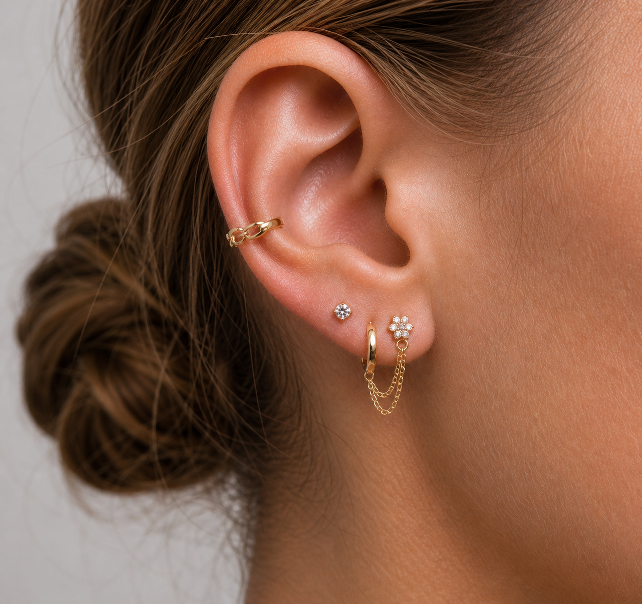 Close-up of an ear with gold hoop earrings and a small stud earring.