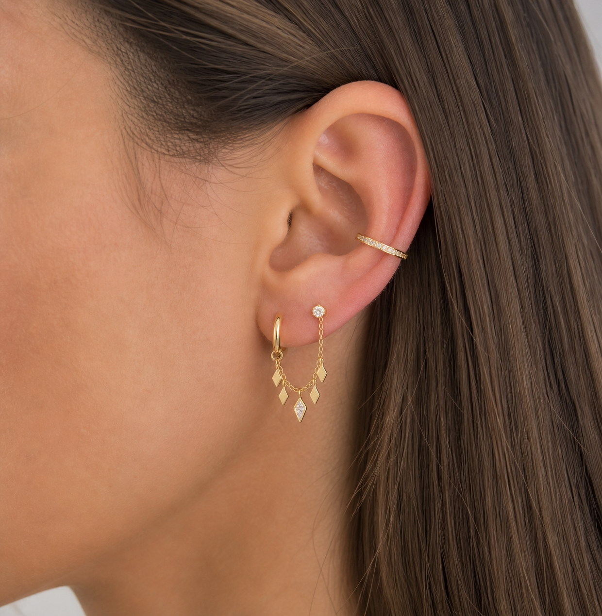 Close-up of a person wearing gold earrings with a blurred background
