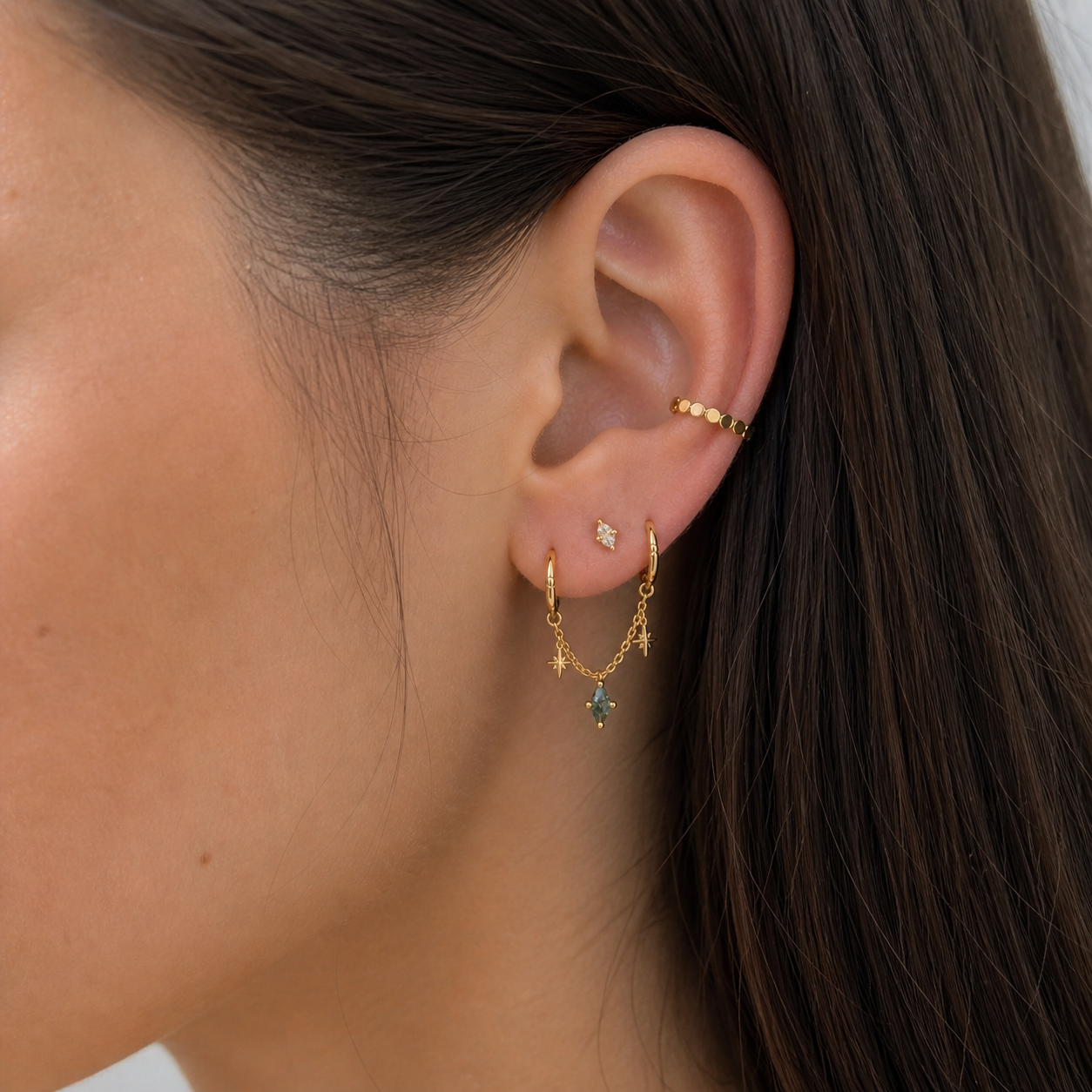 golden chain connecting two hoop earrings with green moss stone in the midle