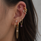 Close-up of an ear with multiple gold earrings on a neutral background