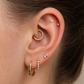 Close-up of an ear with gold hoop earrings and small diamond studs.