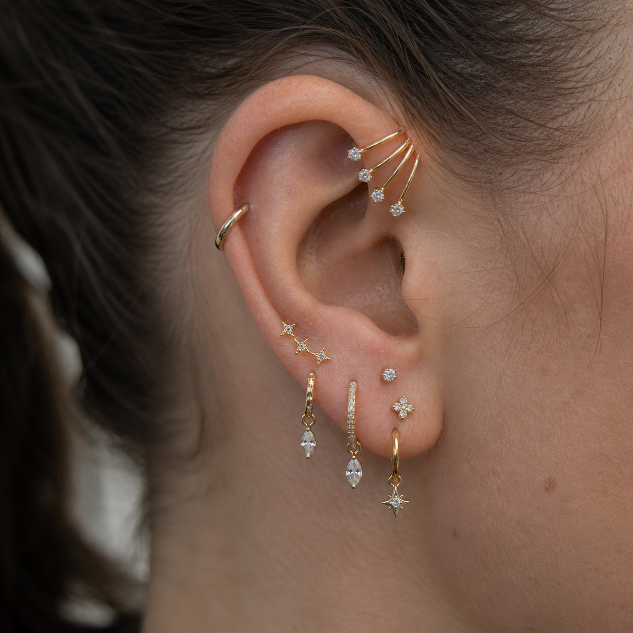 Close-up of an ear with multiple gold and diamond earrings.