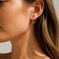 Close-up of a woman wearing gold earrings with a neutral background