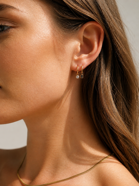Close-up of a woman wearing gold earrings with a neutral background