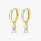 A pair of gold hoop earrings with small clear crystal pendants.