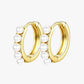 A pair of gold-colored hoop earrings with pearl accents