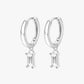 A pair of silver hoop earrings with small clear crystal pendants.