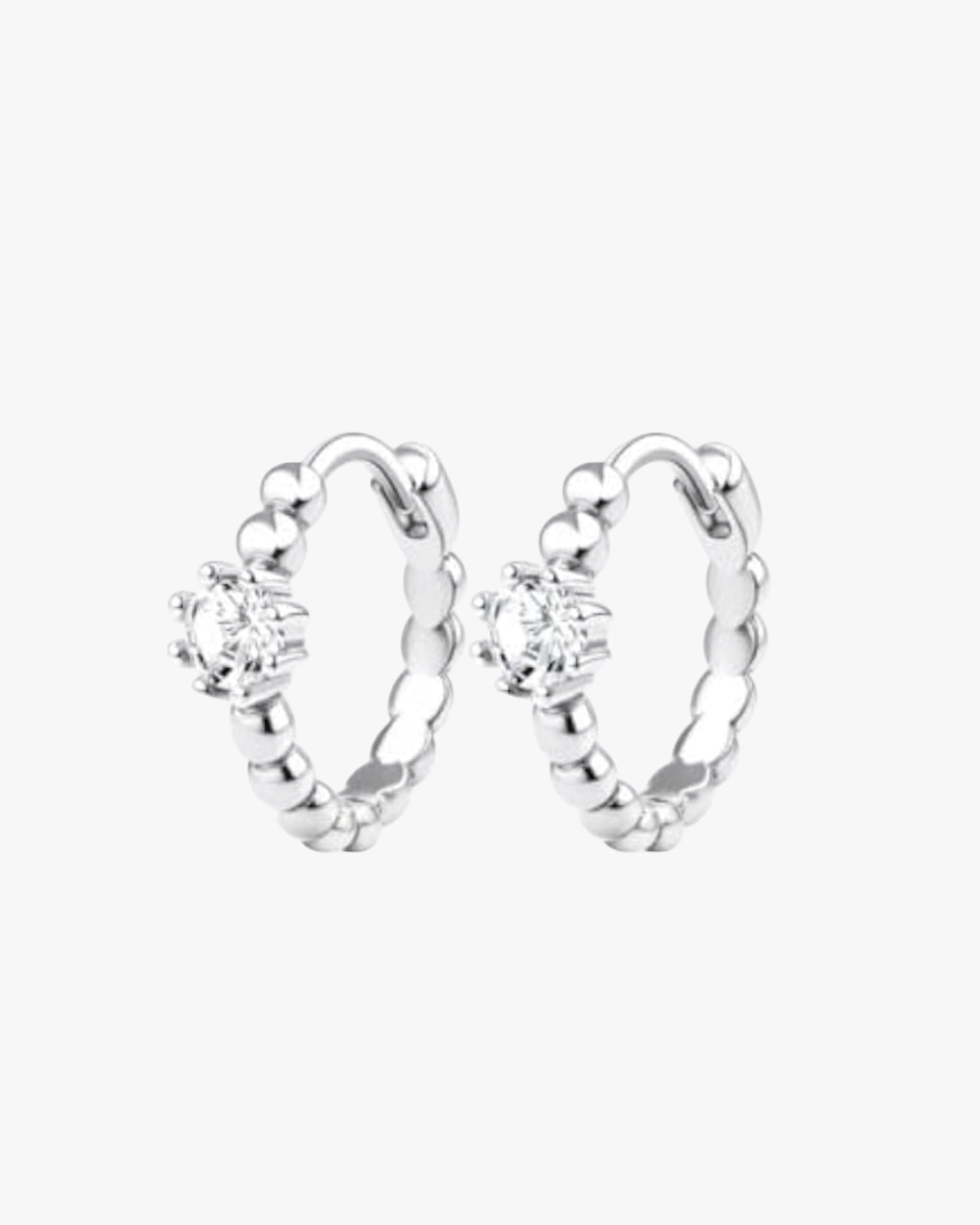 A pair of silver-colored hoop earrings with a small circular embellishment at the top, displayed against a white background.