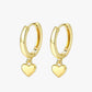 A pair of gold-colored hoop earrings with heart charms attached, displayed against a white background.