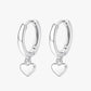 A pair of silver-colored hoop earrings with heart charms attached, displayed against a white background.