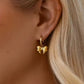 Gold hoop earring worn by a person with blonde hair.