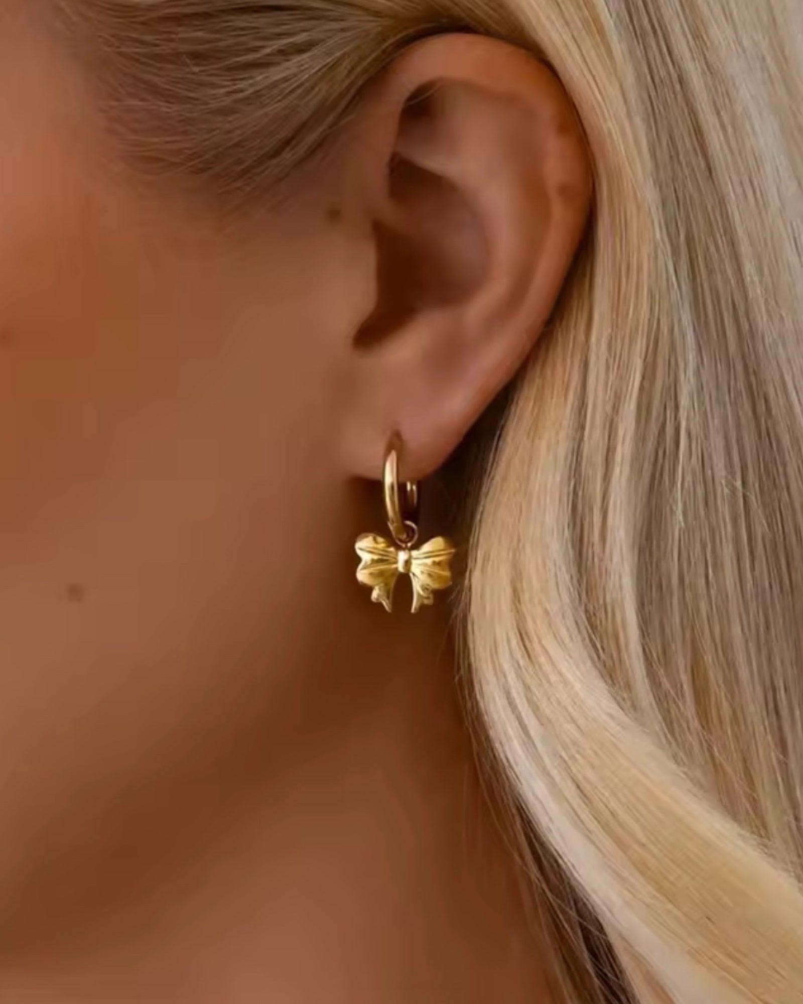 Gold hoop earring worn by a person with blonde hair.