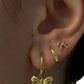 Gold bow-shaped earrings worn on an ear