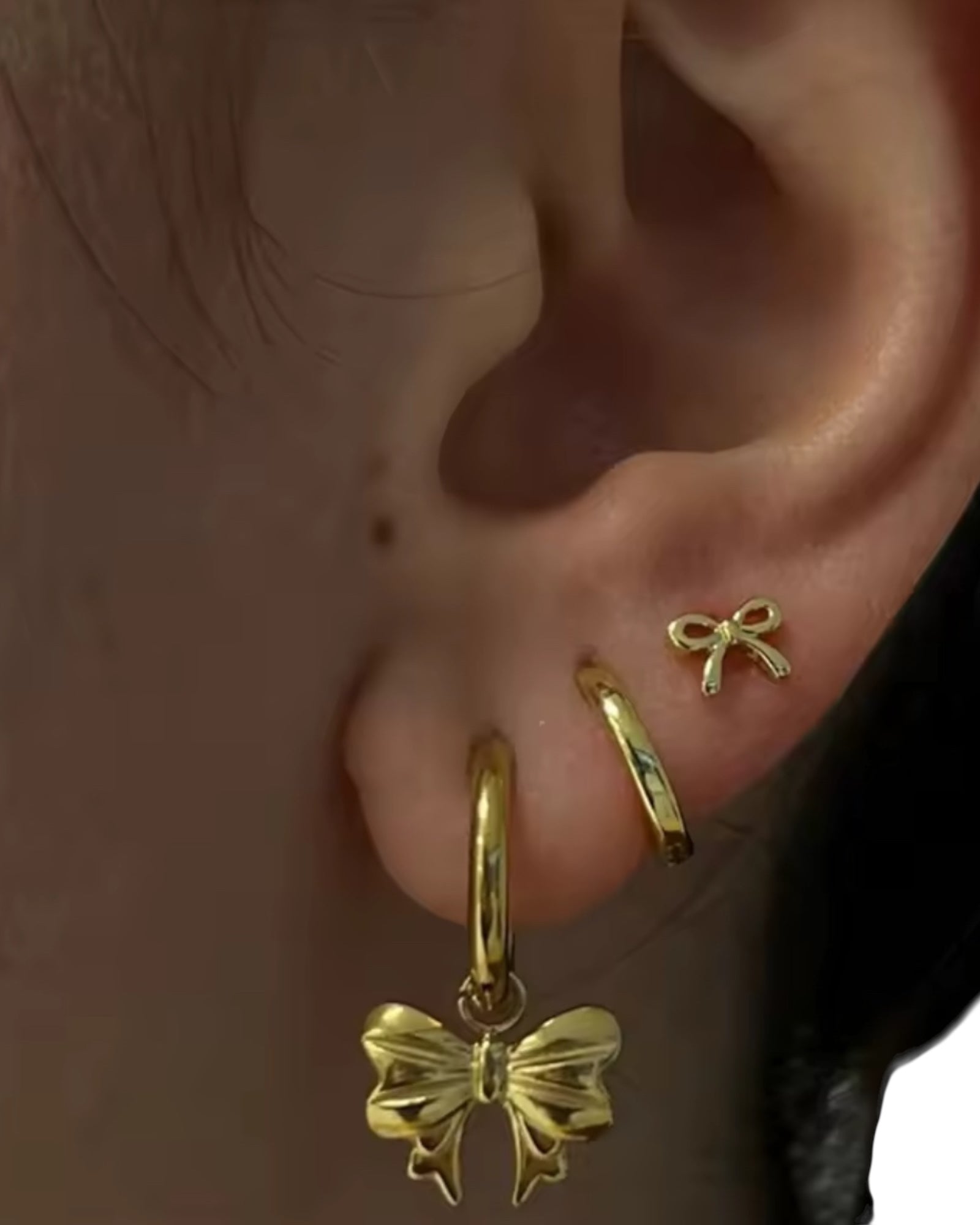 Gold bow-shaped earrings worn on an ear
