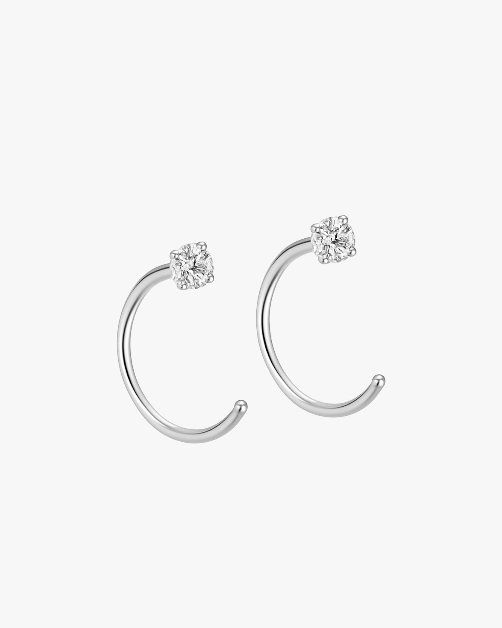 Silver ear cuffs with diamond-like stones on a white background