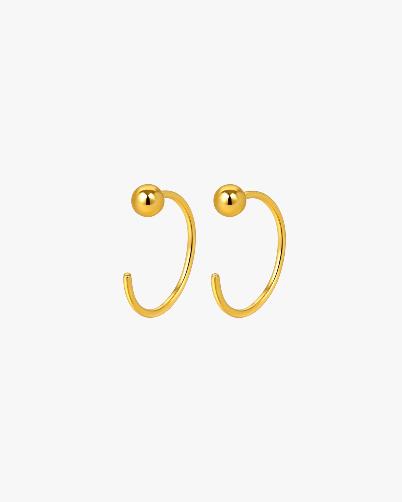 Gold hoop earrings with spherical ends on a white background