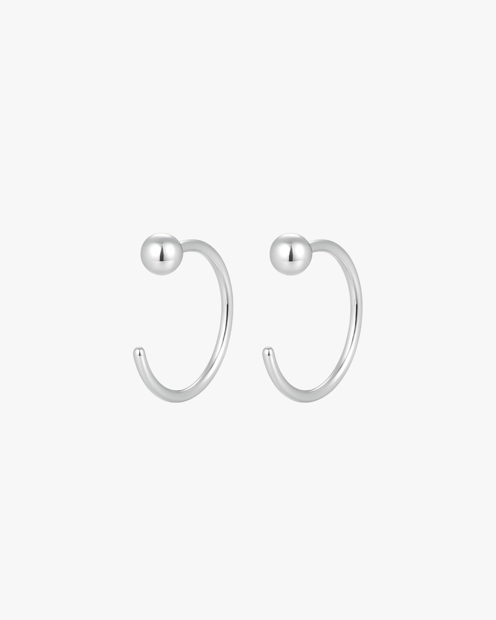 Pair of silver hoop earrings with spherical ends on a white background