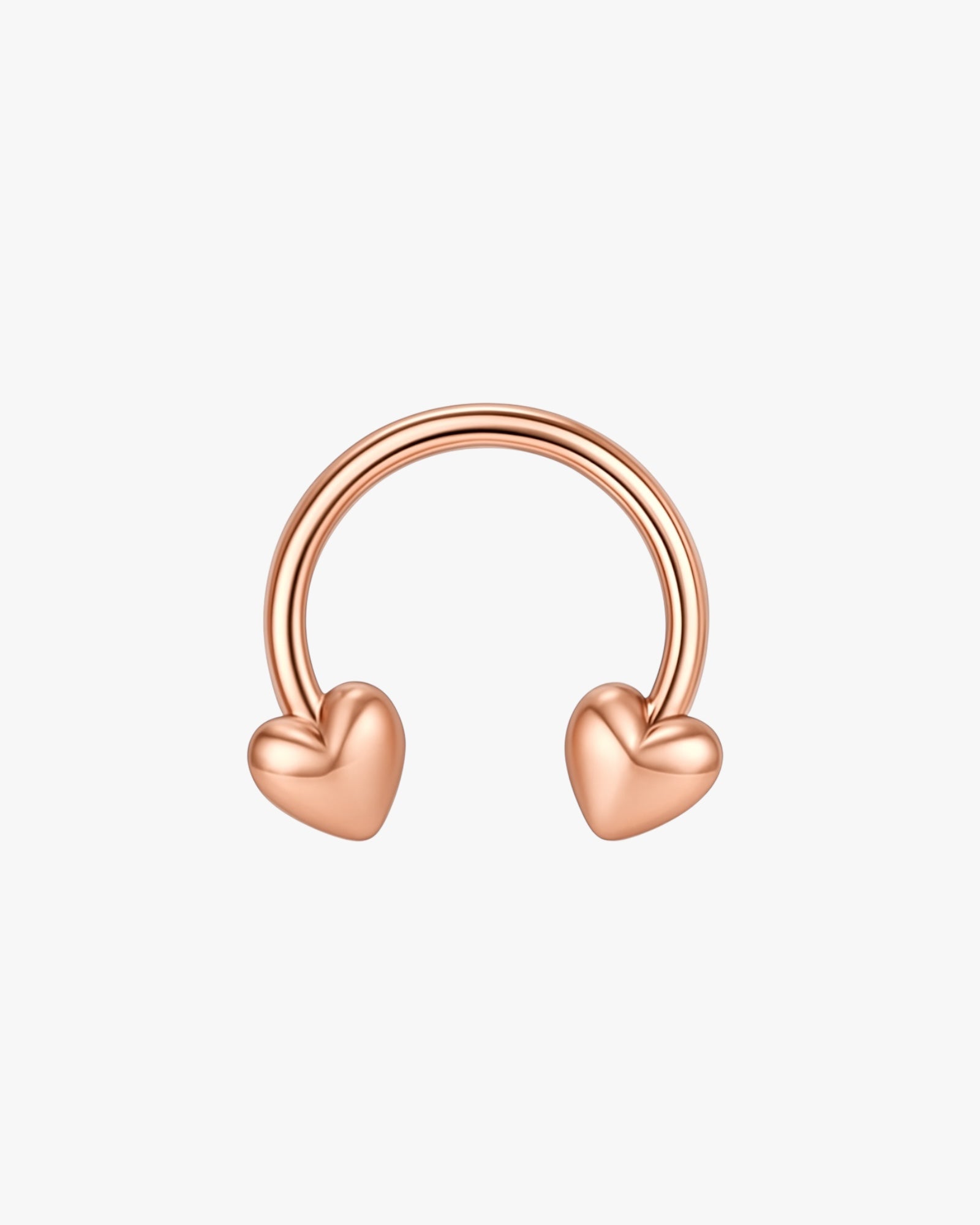 Rose gold hoop earring with heart-shaped ends on a light beige background