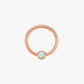Rose gold ring with a small gemstone on a light gray background
