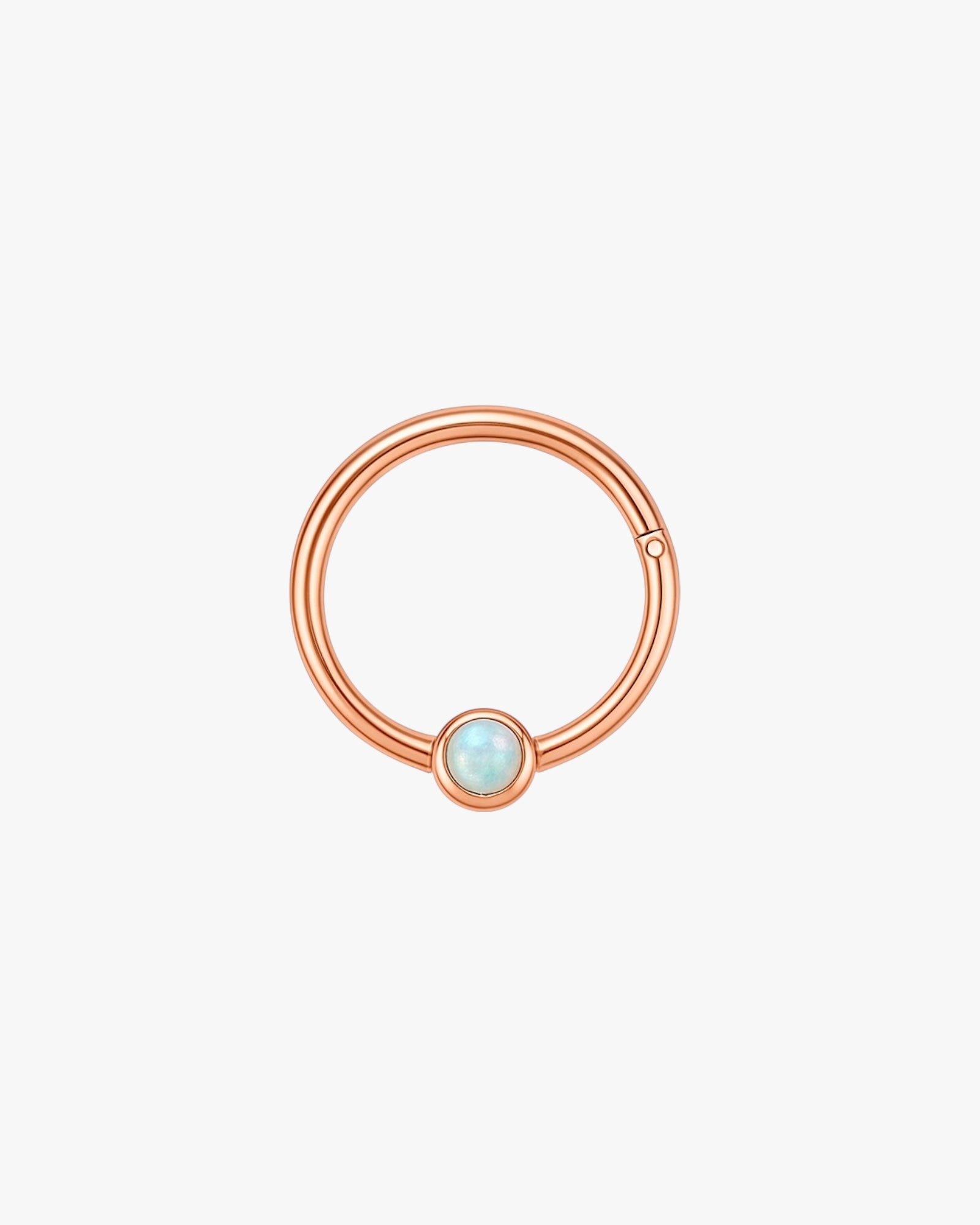 Rose gold ring with a small gemstone on a light gray background