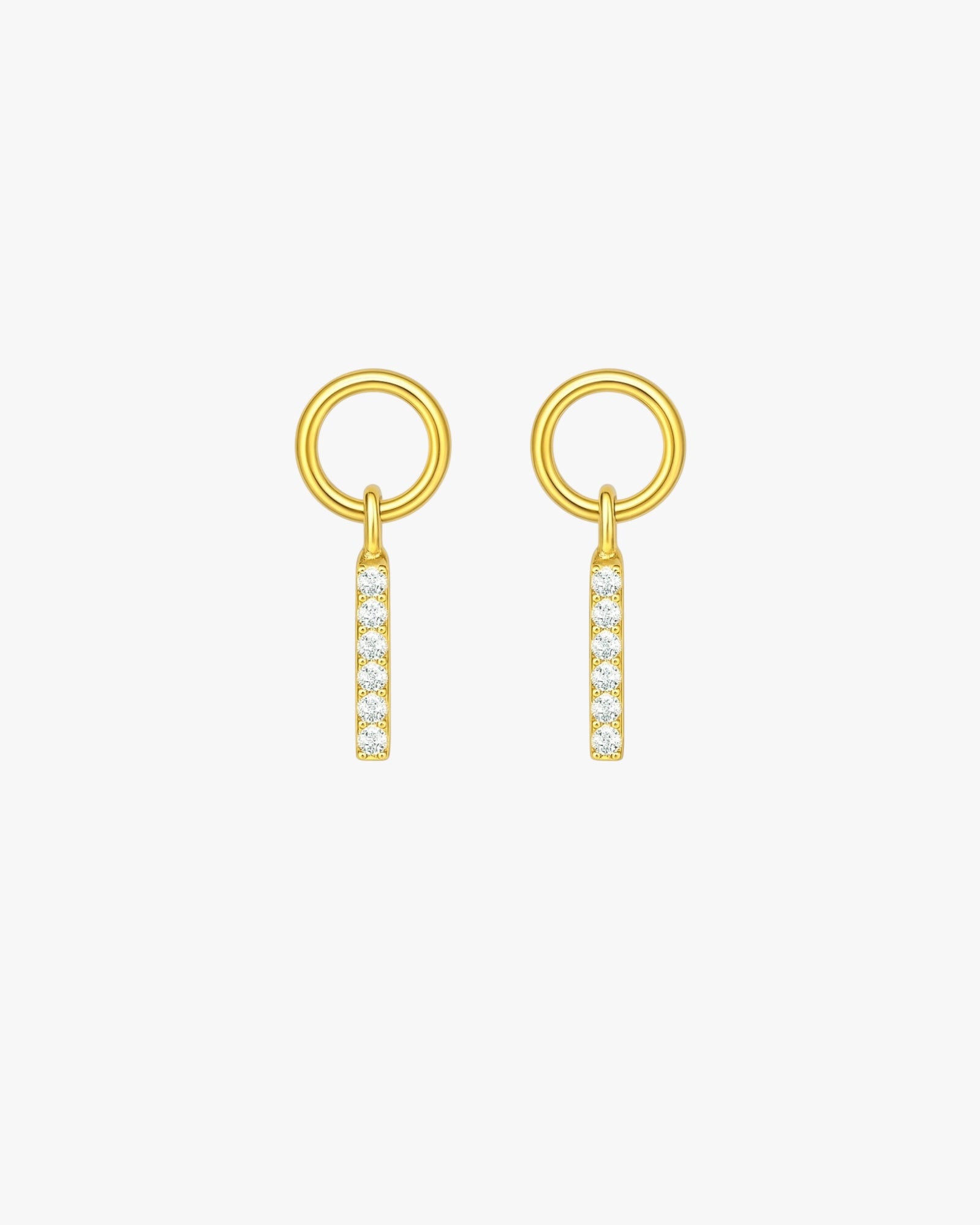 Pair of gold earrings with circular top and bar-shaped bottom on a white background