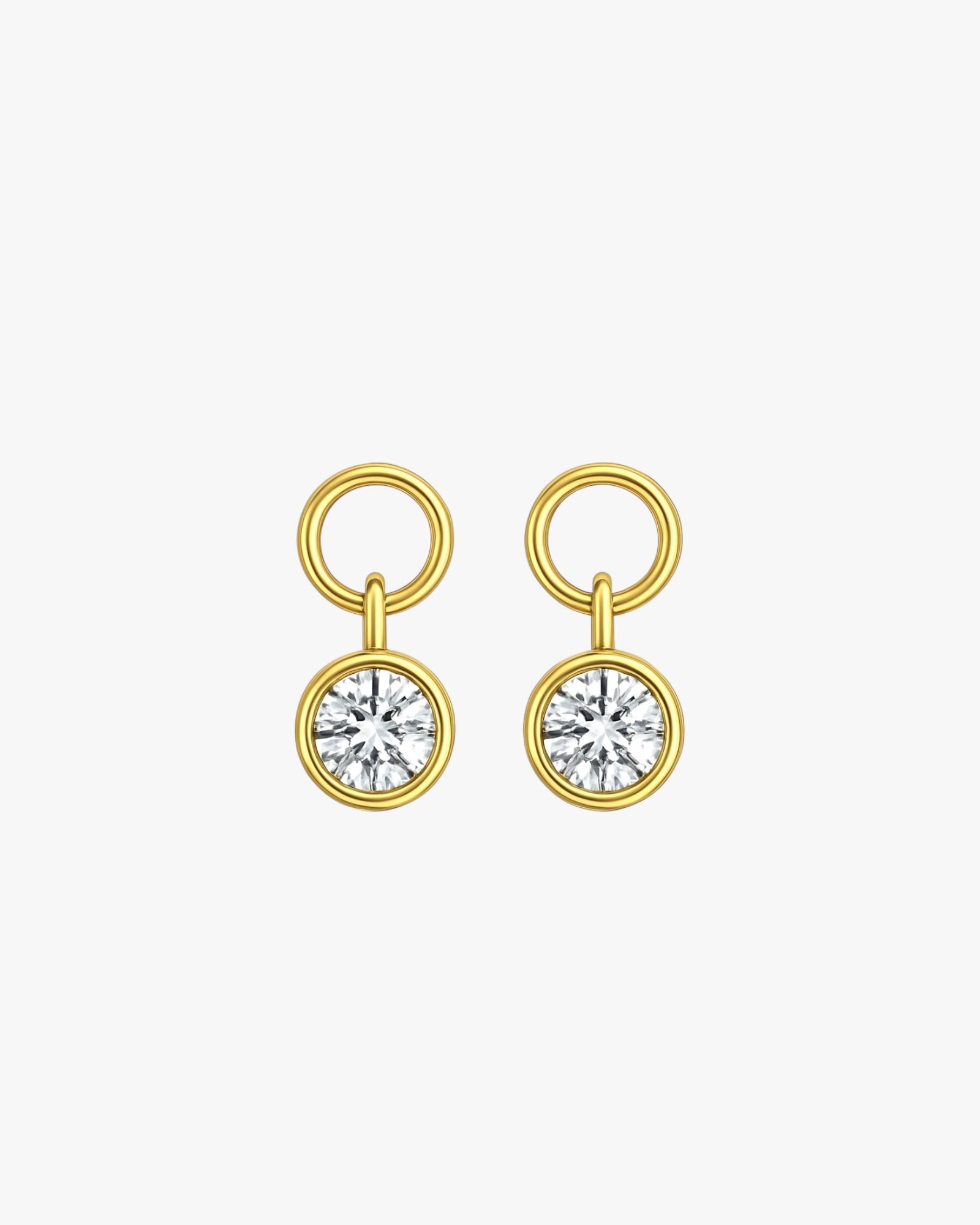 Gold earrings with round gemstones on a light gray background