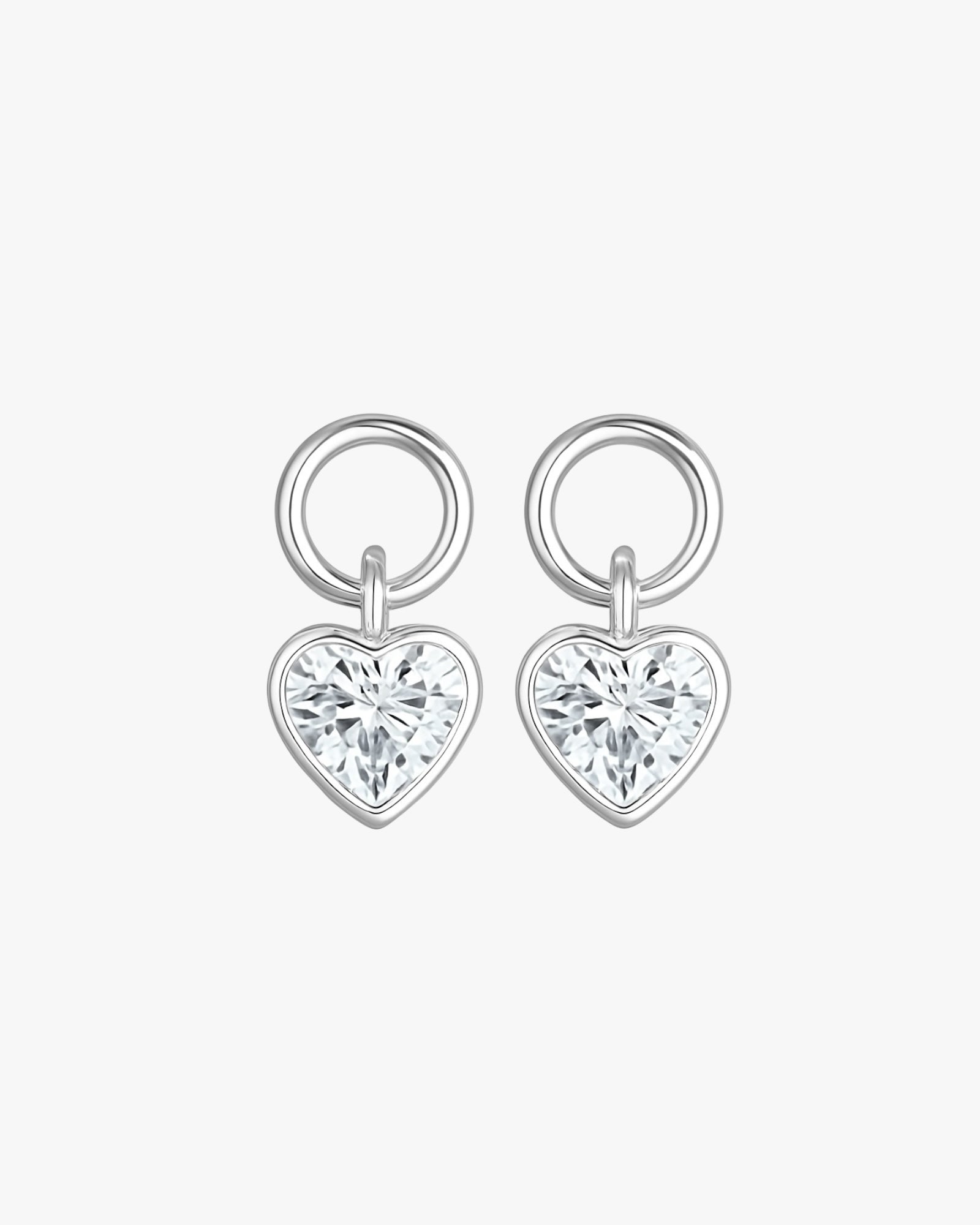 Pair of silver heart-shaped earrings with clear gemstones on a white background
