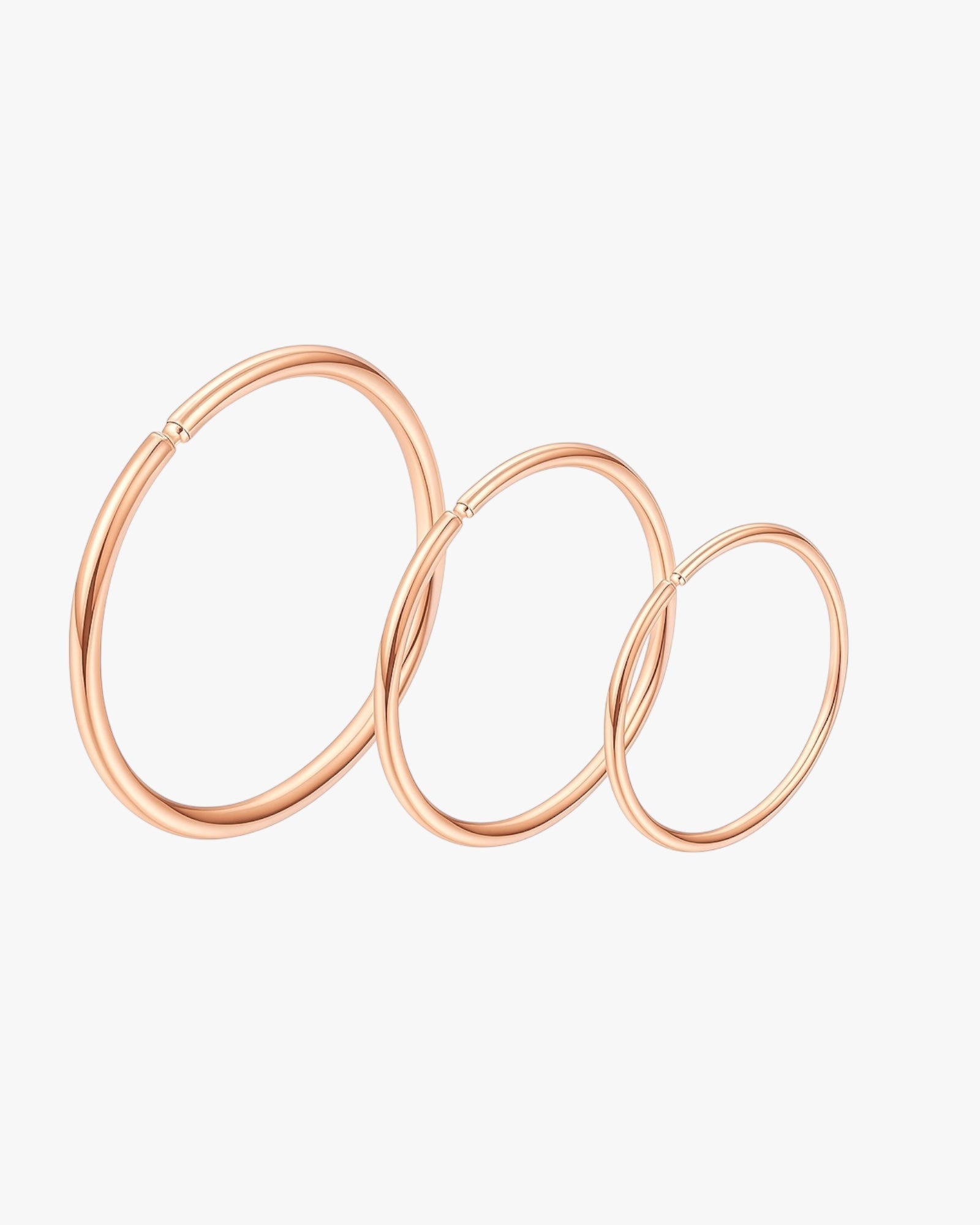 Set of rose gold hoop earrings on a light gray background