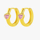 Gold heart-shaped hoop earrings with pink gemstones on a white background