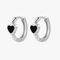 Silver hoop earrings with black heart stones on a white background