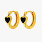 Gold hoop earrings with black heart stones on a white background