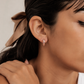 Close-up of a woman wearing pink hoop earrings with a neutral background