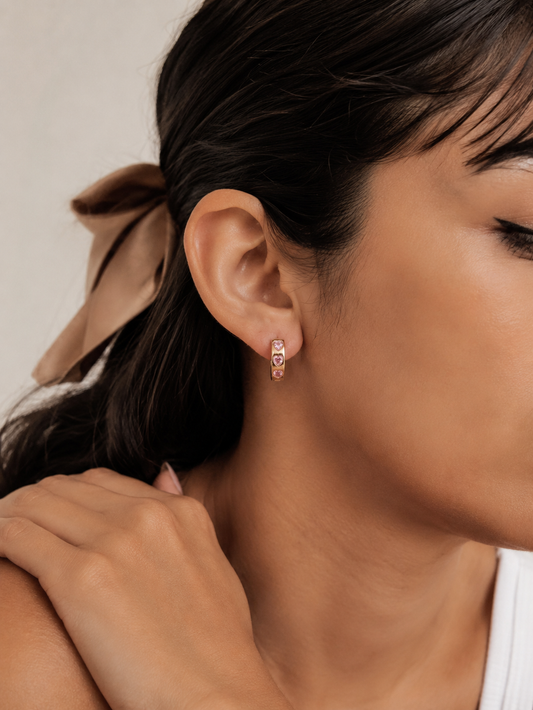 Close-up of a woman wearing pink hoop earrings with a neutral background